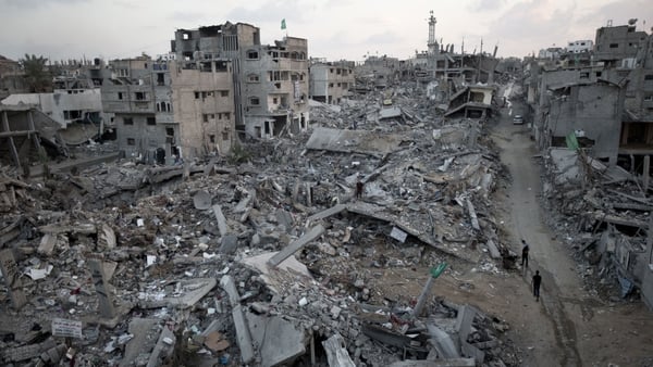 Palestinians walk through rubble of destroyed homes and buildings in Gaza