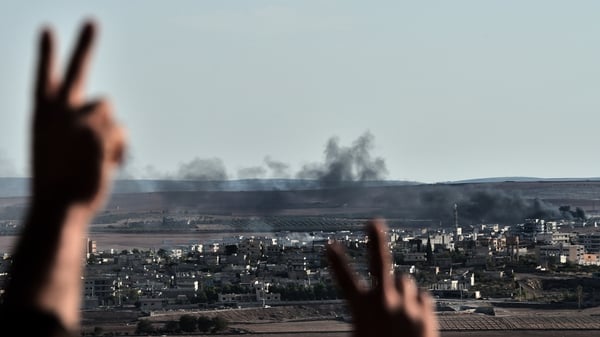 Kurdish people react as they watch smoke billowing from Kobane, as they gather upon a hill overlooking the town