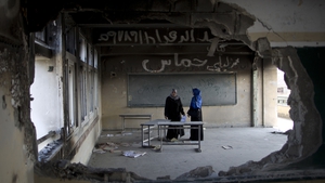 Palestinian teachers stand in a damaged classroom at a United Nations-run school in Gaza City