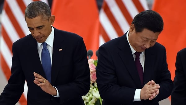 US President Barack Obama returns to his seat as Chinese President Xi Jinping applauds after a toast
