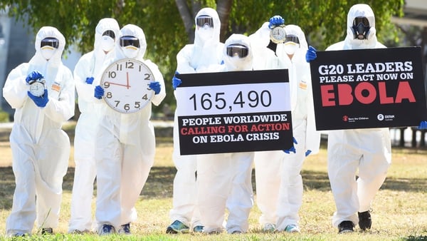 Protesters hold posters and clocks to represent time running out during an Ebola protest event in Brisbane