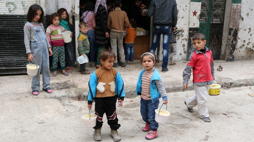 Syrian children stand outside a communal kitchen in the war-torn city of Aleppo
