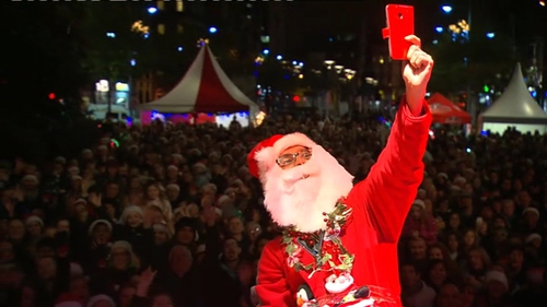 A santa claus attempts to take a selfie with all of the crowd at Geansaí Nollaig