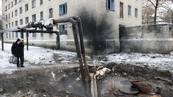 A man stands next to the remains of a heating pipe destroyed by shelling in Donetsk