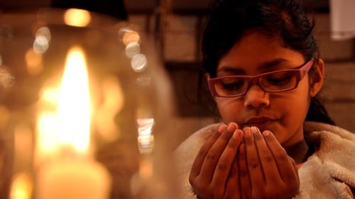 A young girl lights candles and prays for victims of the attack