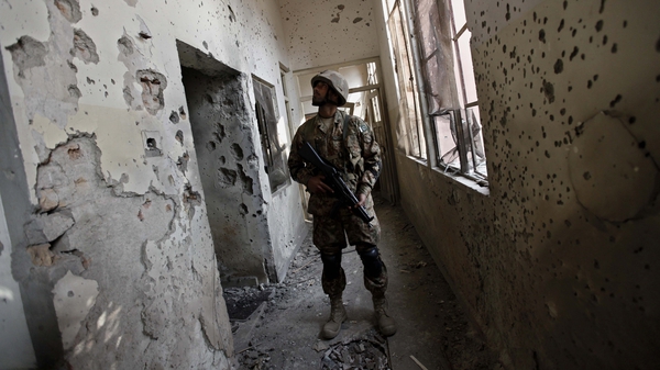 An army soldier looks at a bullet ridden wall of the Army Public School