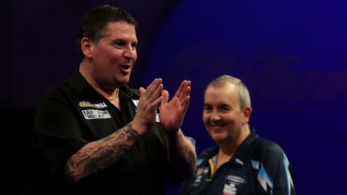 New world champion Gary Anderson salutes the crowd as Phil Taylor looks on