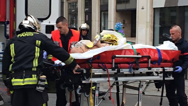 Firefighters carry an injured man on a stretcher in front of the offices of French satirical weekly Charlie Hebdo