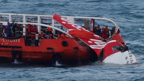 A search and rescue team pulls AirAsia wreckage onto a ship at sea