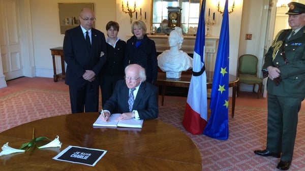 President Higgins signs the book of condolences at the French embassy
