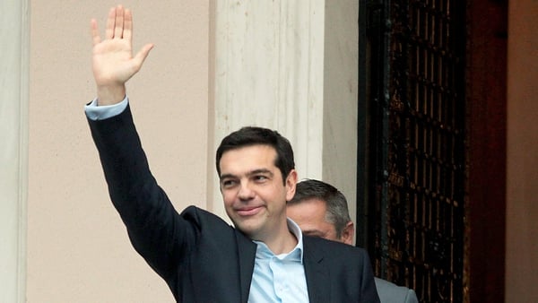 Alexis Tsipras waves on his way into the prime minister's offices in Athens