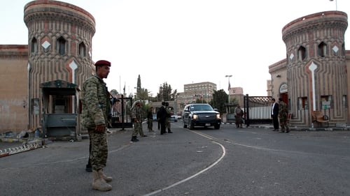 Members of the Huthi group, wearing army uniforms, stand guard outside the presidential palace