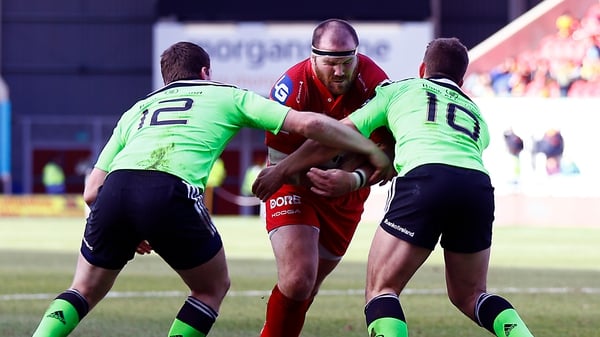 Scarlets' Phil John is tackled by Munster's Ian Keatley and Denis Hurley