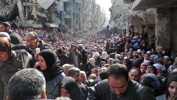 Residents wait in line to receive food aid distributed in the Yarmouk refugee camp on 31 January, 2014 in Damascus, Syria
