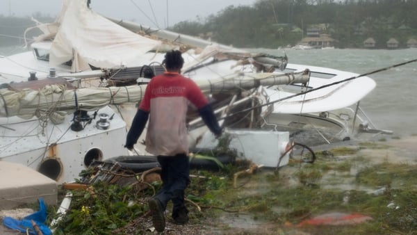 A handout photo provided by UNICEF Pacific of a man walking by severly damaged boats and yachts washed ashore on Vanuatu island
