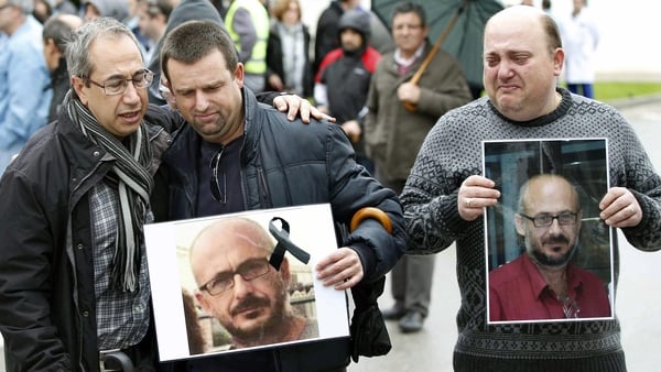 Men hold up pictures of their colleague who died in the crash