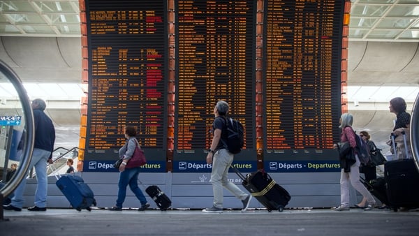 Passengers pass a flight information board at Charles de Gaulle Airport in Paris