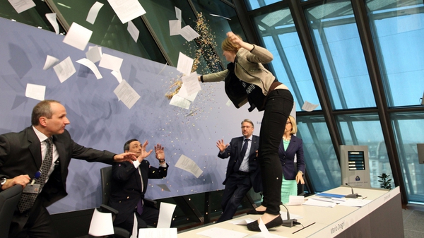 The protester threw paper and glitter at Mario Draghi before being taken away by security