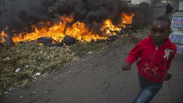 A child runs past burning tires during the xenophobic violence in the Jeppestown area of central Johannesburg