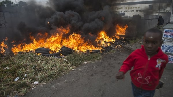 A child runs pass burning tires in the Jeppestown area of central Johannesburg