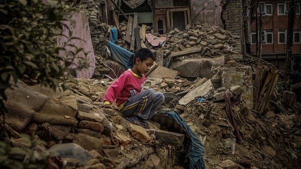 A boy plays on a collapsed house in Kathmandu