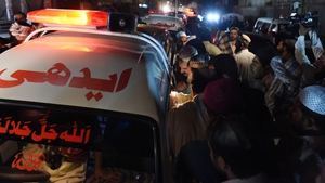 Residents gather around an ambulance carrying bodies of those killed outside the hospital in Quetta