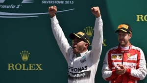 Lewis Hamilton celebrates on the podium at Silverstone, while third-placed Sebastian Vettel looks on