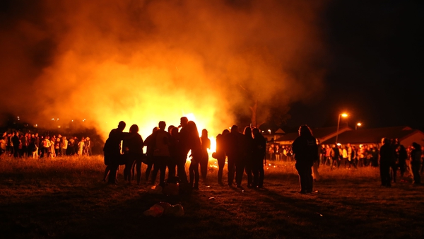 People stand near a small bonfire in the New Mossley area of Belfast