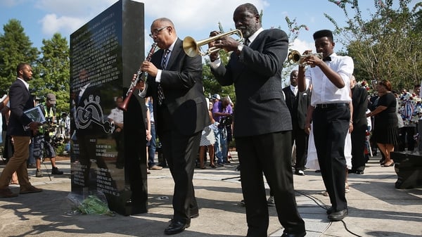 A jazz funeral procession passes the Hurricane Katrina Memorial