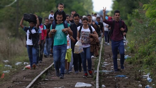 Refugees celebrate as they cross the border from Serbia into Hungary