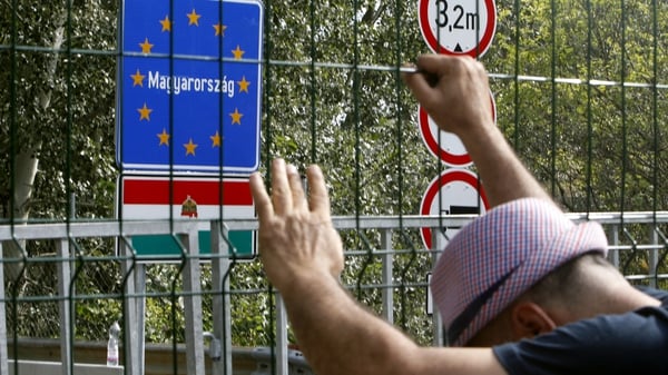 A man holds onto a fence at closed border crossing between Serbia and Hungary in Hogros on the Serbian side