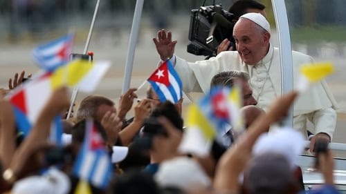 People wave Cuban and Papal flags at Pope Francis ahead of his mass at Revolution Square in Havana