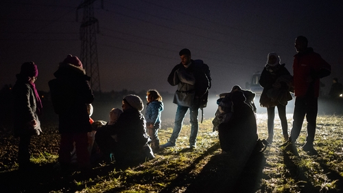 Migrants and refugees rest as they wait to board buses to go to a refugee center after crossing Croatian-Slovenian border in Rigonce
