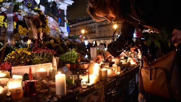 A woman lights a candle on republic square in Paris