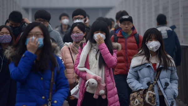 Pedestrians wearing face masks walk through heavy air pollution in Beijing