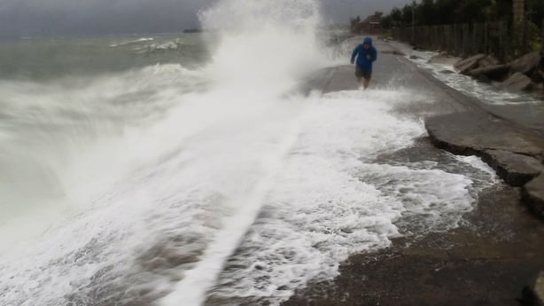 A resident walks past big waves spilling over a wall onto a coastal road in the city of Legaspi, south of Manila, as typhoon Melor approaches