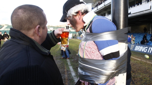 A rugby fan takes a drink during a club game in England