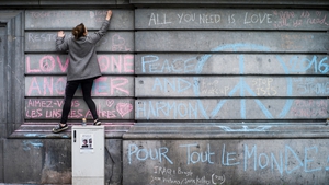 A girl writes a message on a wall in tribute to victims in Brussels