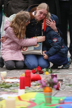A woman embraces her children at The Place de la Bourse as she pays her respects to victims