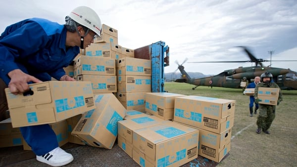 Relief personnel unload boxes of bottled water from a military helicopter after the second major earthquake hit Aso city, Kumamoto