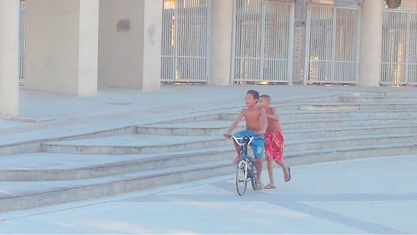 Boys cycle in front of the Maracana stadium