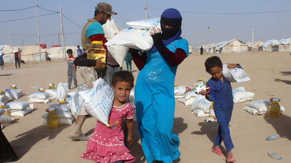 Displaced Fallujah residents carry food distributed by NGOs