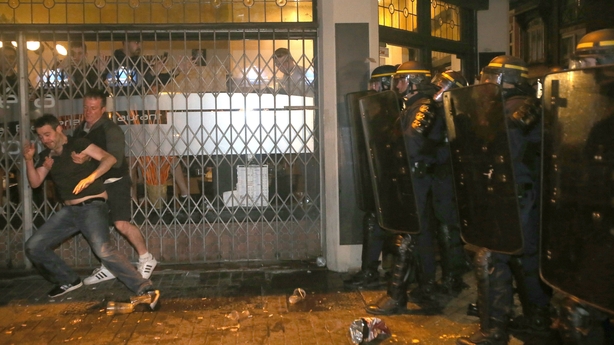 England fan helps another up after he was knocked to the ground by French police in Lille