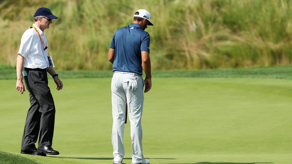 Dustin Johnson chats with a rules official on the fifth green during the final round of the U.S. Open