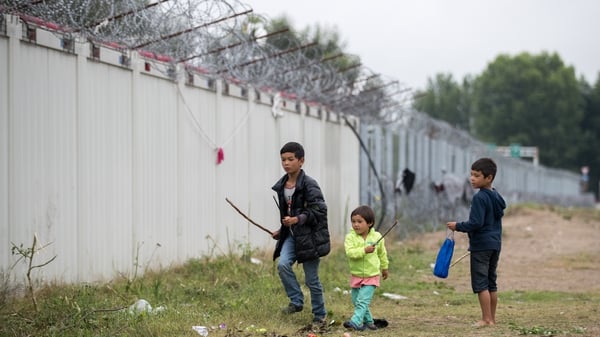 Children play under razor wire at an informal camp close to the E75 Horgas border crossing between Serbia and Hungary