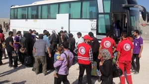 Syrian rebel fighters and their families, helped by volunteers of the Red Crescent, collect their bags from a coach upon their arrival in the rebel-held northwestern city of Idlib