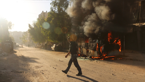 A man walks past a bus set ablaze following a reported air strike in the rebel-held Salaheddin district of Aleppo