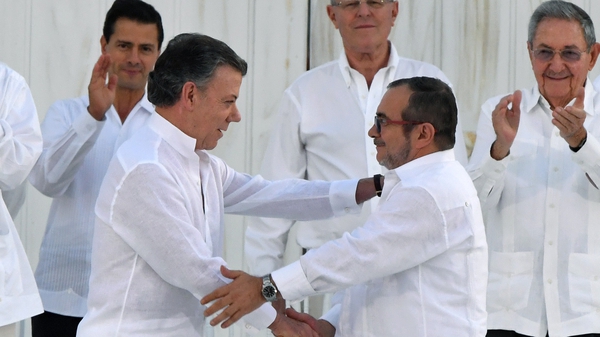 Colombian President Juan Manuel Santos (L) and FARC head Timochenko shake hands after signing the accord