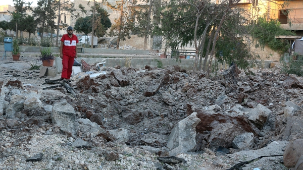 An aid worker inspects the damage at the site of a medical facility after it was reportedly hit by Syrian regime barrel bombs