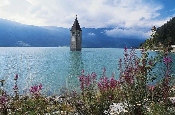 The old bell tower (14th century) of Curon Venosta church rising out of the waters of the artificial lake of Resia, Trentino-Alto Adige, Italy.